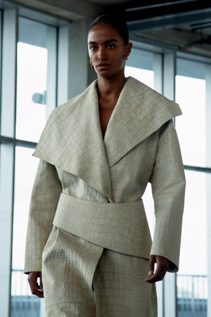 Runway look in neutral tailoring with wide collar at London Fashion Week